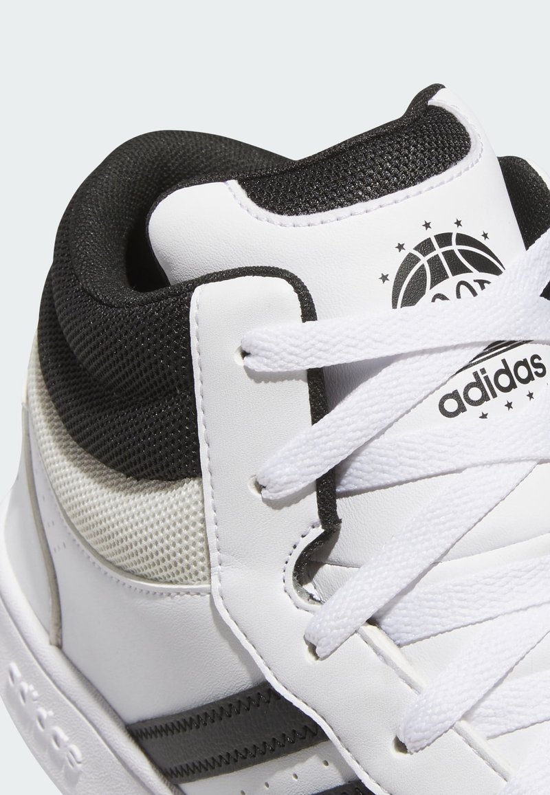 Baskets montantes Adidas blanches et noires avec un col en maille, des lacets blancs et un logo de basket-ball sur la languette.