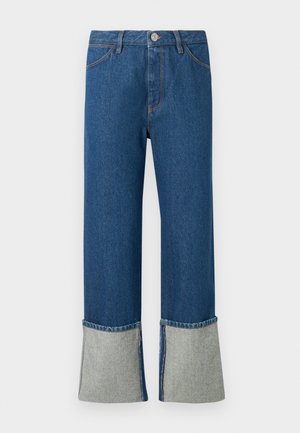 Mørkeblå denim jeans med brede, lyseblå mansjetter. Har en frontlukkemekanisme med knapp, sømdetaljer, og fire lommer. Klassisk rett ben-design.