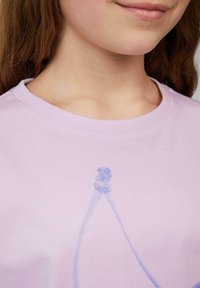 Lila Baumwoll-T-Shirt mit Rundhalsausschnitt und kurzen Ärmeln, versehen mit einem blauen Grafikdruck einer Figur. Glatte Textur mit lässiger Passform.