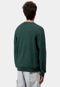 Sudadera verde oscuro con cuello redondo, fabricada en una tela suave. Presenta puños y dobladillo acanalados, con un estilo sin logotipos o patrones visibles.