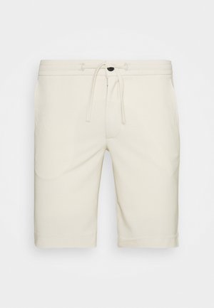 Pantaloni corti beige chiaro realizzati in tessuto morbido, dotati di una vita elasticizzata con cordino, tasche laterali e un taglio dritto.