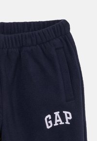 Mornarsko modri flis hlače za tek s elastiko v pasu, ki vsebujejo bel "GAP" logotip in stranske žepe. Mehka tekstura z zasnovo sproščenega kroja.