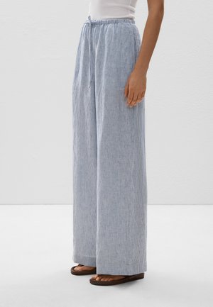 Pantaloni ampi a righe leggeri in blu e bianco, con vita regolabile e vestibilità rilassata. Abbinati a sandali piatti marroni.
