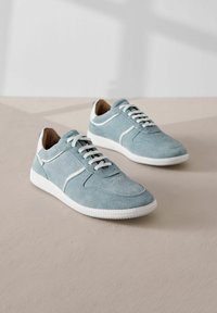 Baskets en daim bleu clair avec des accents blancs, bout rond, tige texturée et semelle en caoutchouc blanche. Présente un laçage traditionnel et des coutures contrastantes.