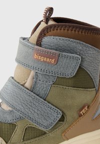Wysokie buty sportowe wykonane z mieszanki szarej skóry, zielonego materiału i brązowych akcentów. Posiadają paski na rzepy oraz teksturowaną powierzchnię.