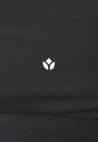 Black fitted fabric with a smooth texture, featuring a small white floral logo at the center. No additional patterns or details present.