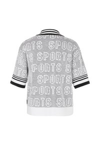 Chemise en maille blanche à manches courtes avec col et poignets rayés noirs, comportant le mot répété "SPORTS" dans un motif perforé.