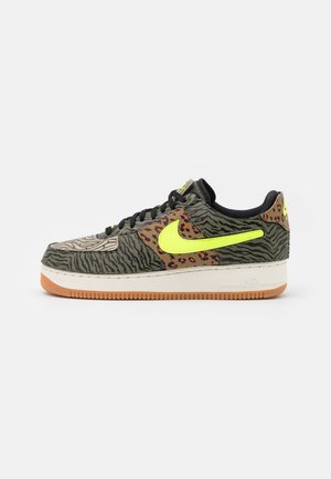 Niskie sneakersy z wzorami zwierzęcymi w kolorach zielonym, brązowym i beżowym, neonowo-żółwym logo Swoosh, czarne sznurówki i jasnobrązowa podeszwa z białą środkową warstwą.
