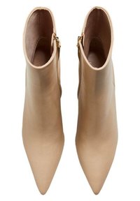 Botines de cuero beige con punta puntiaguda, con una textura suave y cremalleras laterales para facilitar su uso.