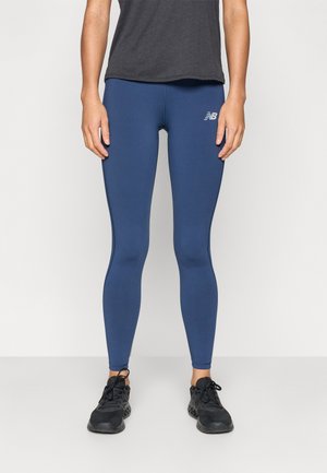 Leggings atléticos azul-marinho feitos de material elástico, com um design ajustado e um pequeno logótipo branco na parte superior da coxa.