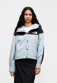 Ανοιχτό μπλε κοντό μπουφάν με μαύρο πάνελ, τσέπες στο μπροστινό μέρος και κουκούλα. Διαθέτει κλείσιμο με κουμπιά και λογότυπο στο στήθος. Λείος υφασμάτινος τύπος.