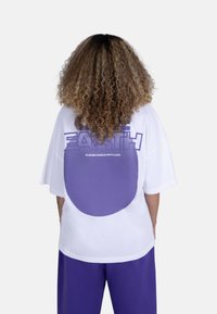 White oversized T-shirt featuring a large purple circle graphic on the back and "EARTH" text above in bold purple letters.