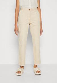 Beżowe lekkie spodnie o prostym kroju, zapinane na guzik, z kieszeniami bocznymi. Noszone z kremowymi, falbanianymi sandałami na płaskiej podeszwie.