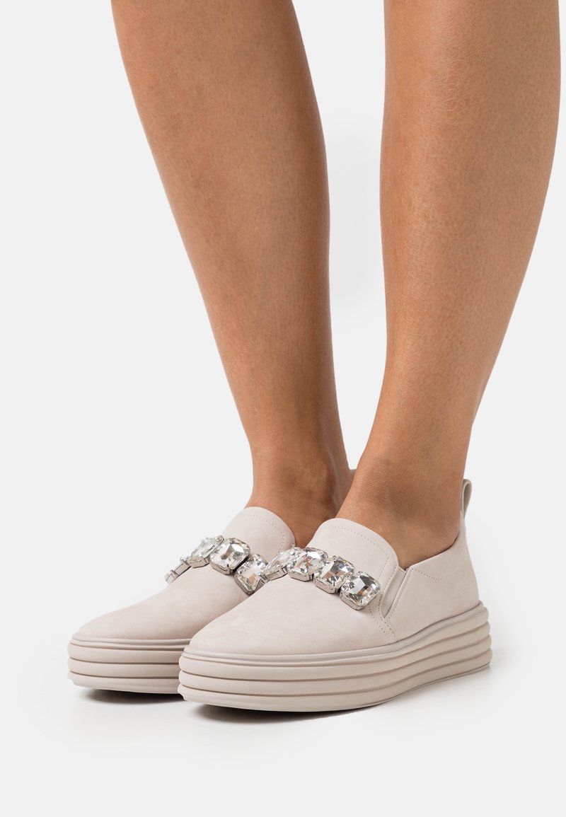 Helle beige Slipper aus Wildleder mit einer dicken Plattform und einer dekorativen metallischen Kettenakzentierung an der Vorderseite.