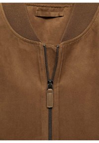 Veste en daim marron avec fermeture éclair métallique noire, col côtelé et languette de fermeture éclair en cuir cousu.