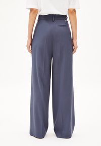 Weite Hosen in Dunkelblau, aus einem glatten Stoff gefertigt, mit hoher Taille, gefälteltem Design und einer einzelnen Gesäßtasche.