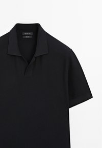 Polo shirt nera realizzata in tessuto testurizzato. Presenta un colletto corto e una patta con un sottile design a V.