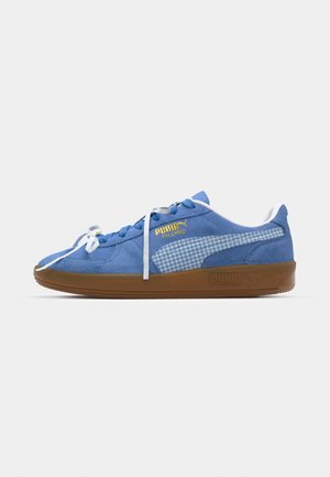 Blå suedesneakers med hvite snørebånd og rutete sidepanel. Har en brun gummisåle og gulllogo-detaljering.