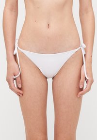 Białe bikini dolne z regulowanymi wiązaniami po bokach, gładką teksturą i minimalistycznym designem o niskim kroju.