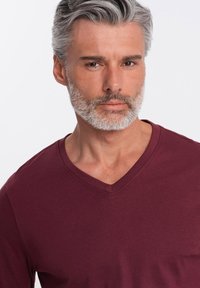 Camiseta burdeos de cuello en V con una textura suave, manga corta y un corte relajado, que presenta un escote liso y un estilo casual.