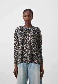 Langermet topp i svart og beige dyreprint, med rund hals, avslappet passform og mykt teksturert stoff. Kombinert med lyseblå jeans.