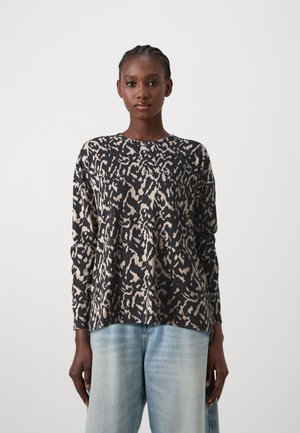 Long-sleeve top in black and beige animal print, featuring a crew neckline, relaxed fit, and soft textured fabric. Paired with light blue jeans.