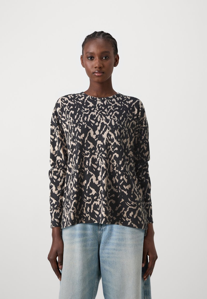 Langermet topp i svart og beige dyreprint, med rund hals, avslappet passform og mykt teksturert stoff. Kombinert med lyseblå jeans.