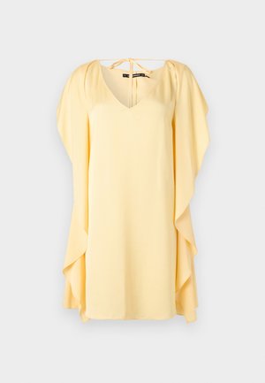 Robe courte jaune clair avec des manches cape fluides et un décolleté en V noué à l'arrière du col.