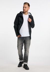 Sort hættejakke med grå for, lynlås og trykknaplukninger, parret med en almindelig hvid t-shirt og grå jeans. Sorte sneakers fuldender looket.