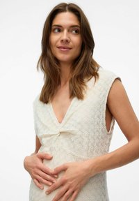 Robe crème clair avec un motif en diamant texturé, décolleté en V et manches courtes. Présente un détail en nœud à la taille.
