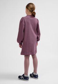 Lila Baumwollkleid mit Puffärmeln, knielang, kombiniert mit hellrosa Leggings und marineblauen Turnschuhen. Einfaches Design und weiche Textur.