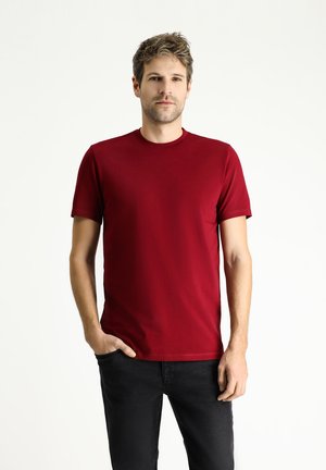 Rode t-shirt met korte mouwen, gemaakt van gladde katoenen stof, met een ronde halslijn en een getailleerd silhouet, gecombineerd met zwarte jeans.