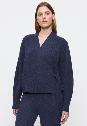 Marinefarbener Wickelpullover aus strukturiertem Strickmaterial, mit langen Ärmeln, tiefem V-Ausschnitt und einer gebundenen Taillenpartie. Insgesamt lockere Passform.