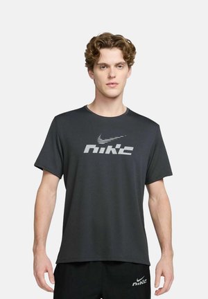 Schwarzes Kurzarm-Nike-T-Shirt aus glattem Stoff; verfügt über ein großes, erhabenes graues Nike-Logo auf der Vorderseite.