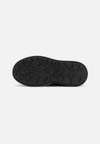 Black rubber shoe sole with a textured, wavy pattern for traction. The edge is rounded, and the design is smooth with no visible logos.