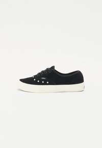 Black suede sneakers featuring a flat, white rubber sole and silver studs along the side. Laced design and cushioned collar.