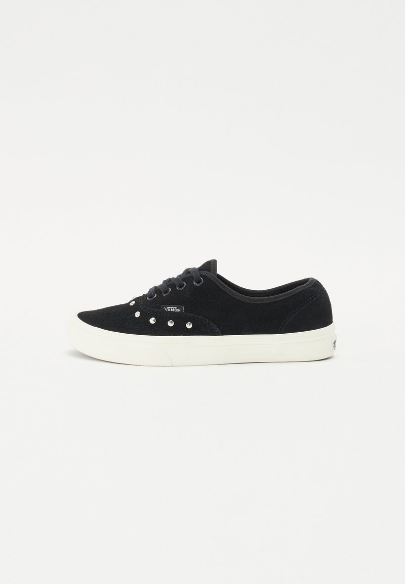 Black suede sneakers featuring a flat, white rubber sole and silver studs along the side. Laced design and cushioned collar.