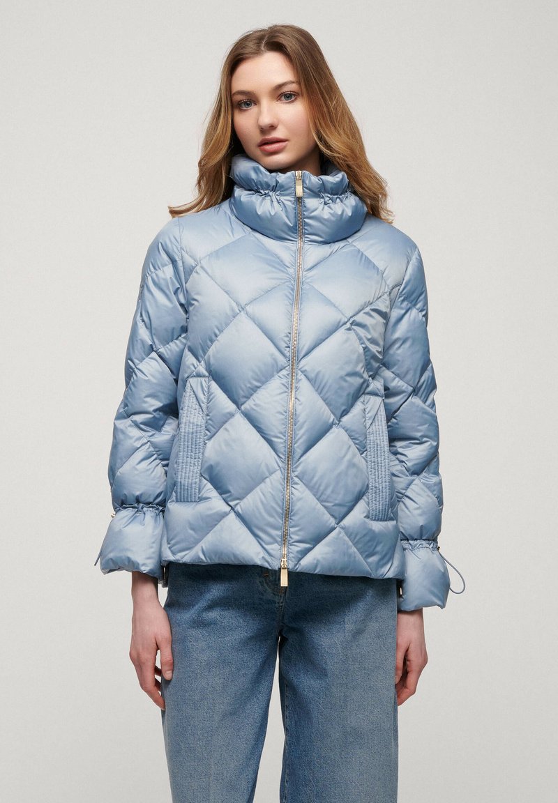 Light blue quilted puffer jacket with high collar, gold zipper, and side pockets. Features a cropped design and elasticated cuffs.