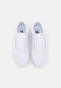 Paire de baskets basses blanches avec des lacets blancs et un logo sur la semelle intérieure, vue de dessus sur un fond clair.