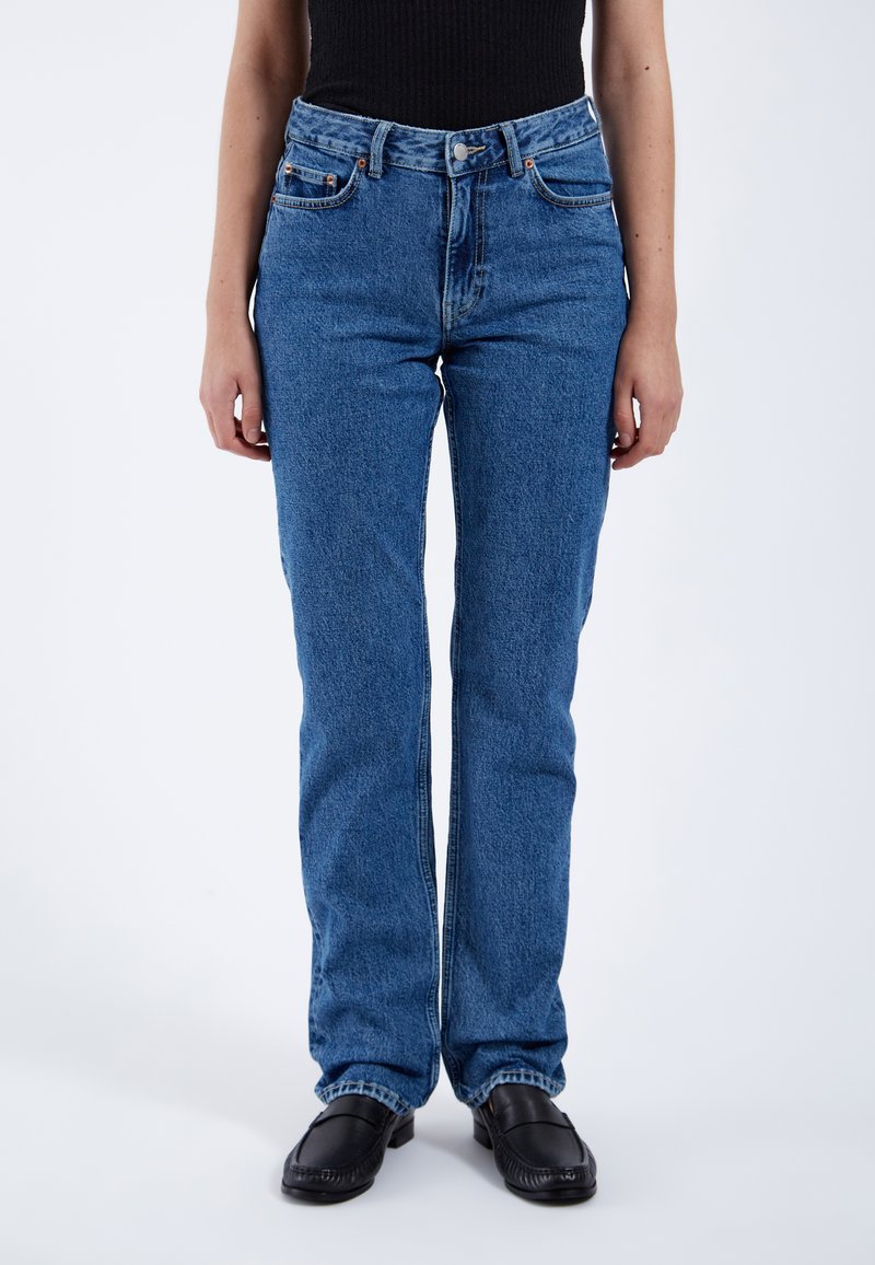 Jeans de mezclilla azul claro con un diseño de pierna recta, cinco bolsillos y detalles de costura sutil. Cierre frontal con botón. Tejido texturizado.