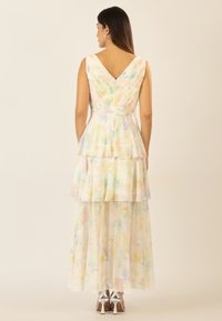 Abito senza maniche a scollo a V con design a strati. Realizzato in tessuto floreale pastello leggero. Presenta una zip sul retro e tacchi a spillo argentati.