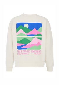 Sweatshirt couleur crème avec un graphique rectangulaire représentant des montagnes en rose, vert et bleu, et du texte en rose en bas.