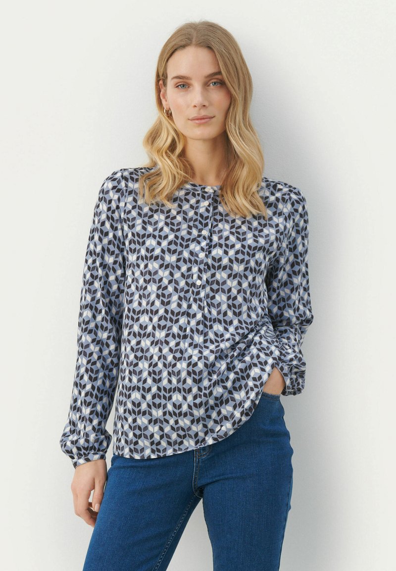 Camicia con bottoni caratterizzata da un motivo geometrico nei toni di blu, navy e bianco; maniche lunghe con polsini arricciati; orlo curvato; realizzata in tessuto leggero.