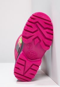 Semelle rose vif d'une chaussure de sport pour enfants avec des crampons profonds, taille 25/8, et le logo "RAW TERRAIN" sur un fond blanc.
