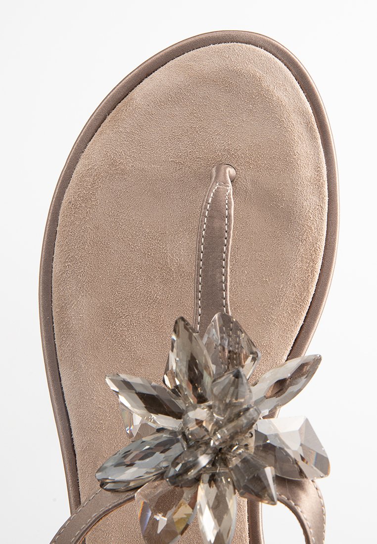 Beige Wildleder Flip-Flops mit einer strukturierten Fußbett und einem dekorativen Blumenakzent aus klaren, facettierten Kristallen in der Mitte.