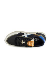 Sneaker atletico nero con tessuto testurizzato, dettagli bianchi e blu, e lacci neri. Include un'etichetta beige e una suola in gomma. Vista dall'alto.