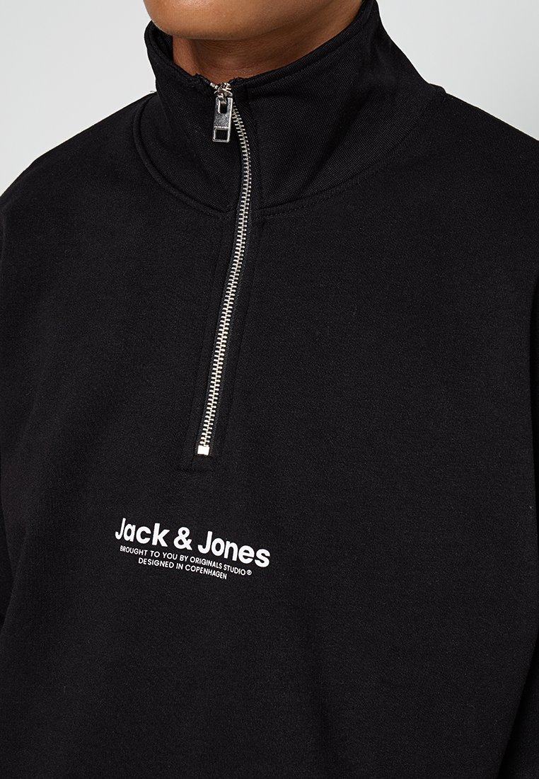 Sudadera negra con media cremallera hecha de tela suave. Presenta una cremallera plateada y el logotipo impreso en blanco "Jack & Jones" en el pecho.