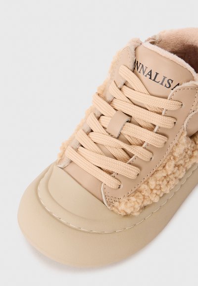 Beige sneakers med tykke snørebånd, fluffy ull-lignende detaljer på siden, og polstret innside for ekstra varme og komfort.