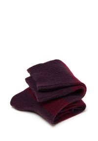 Calze di lana piegate a strisce viola scuro e bordeaux su uno sfondo bianco.