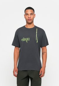 Mørkegrå bomulds T-shirt med grøn Nike branding og grafik. Korte ærmer, rund hals, lige pasform. Minimalistisk design, ingen mønstre.